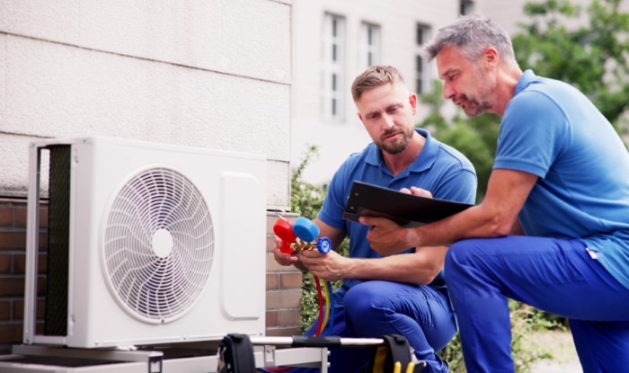 HVAC technicians reviewing an outdoor air conditioning unit in Herriman, UT