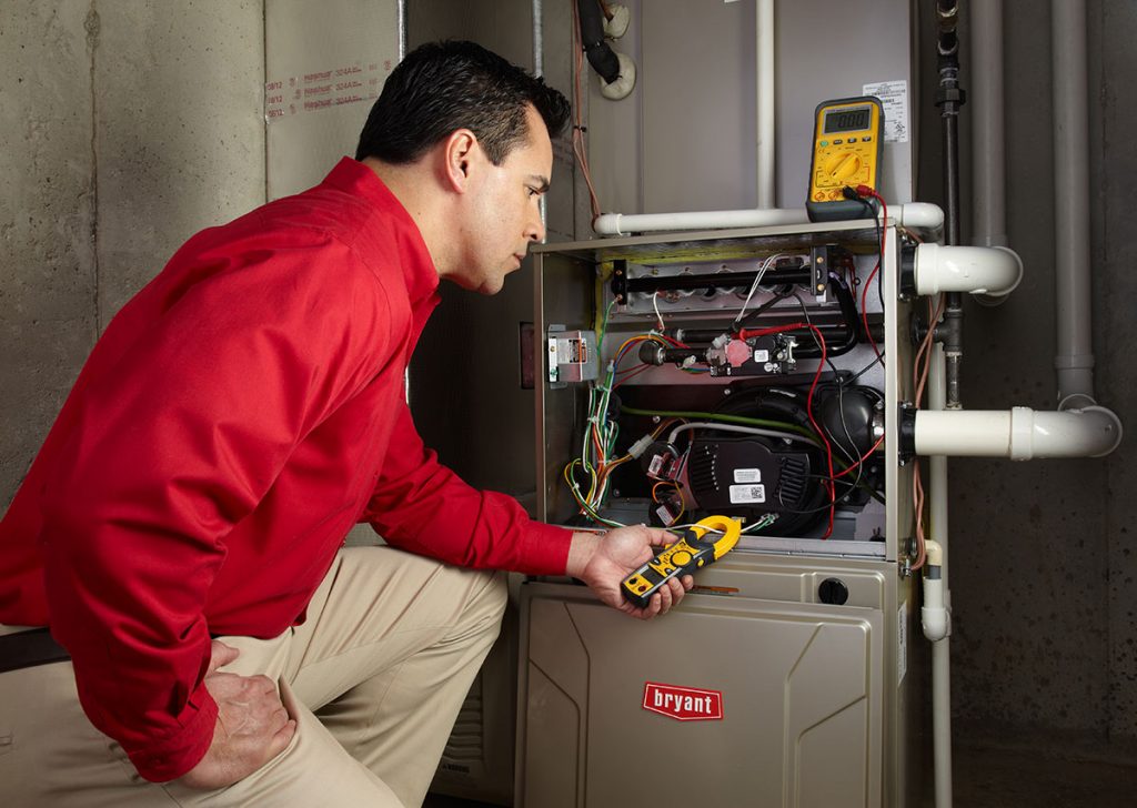Heating and air conditioning technician servicing an indoor furnace in Herriman, UT