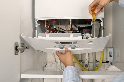 HVAC technician repairing an indoor boiler in Herriman