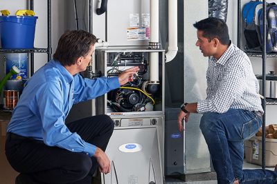HVAC technician explaining furnace repair and maintenance to a homeowner in Herriman, UT