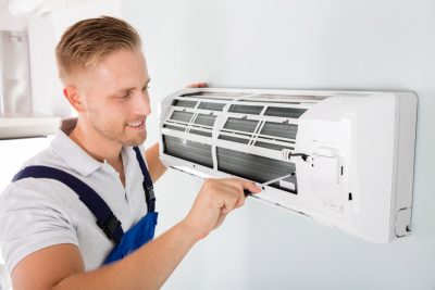 HVAC technician cleaning and repairing a ductless mini split AC in Herriman, UT