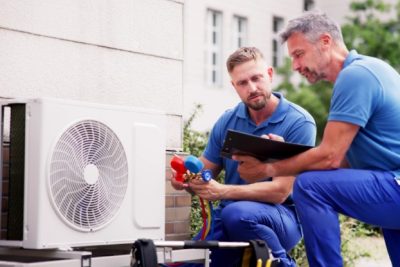 HVAC technicians reviewing an outdoor air conditioning unit in Herriman, UT