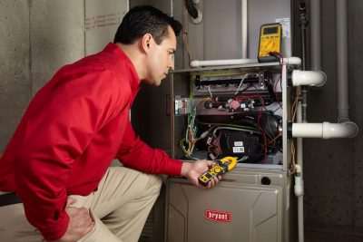 Heating and air conditioning technician servicing an indoor furnace in Herriman, UT